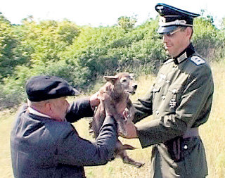 Староста передает вытащенного из логова волчонка немецкому офицеру