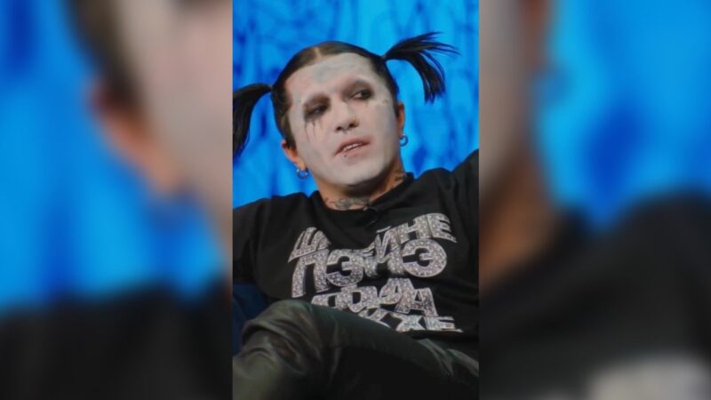 Ганвест с хвостиками и белым гримом сидит на синем фоне